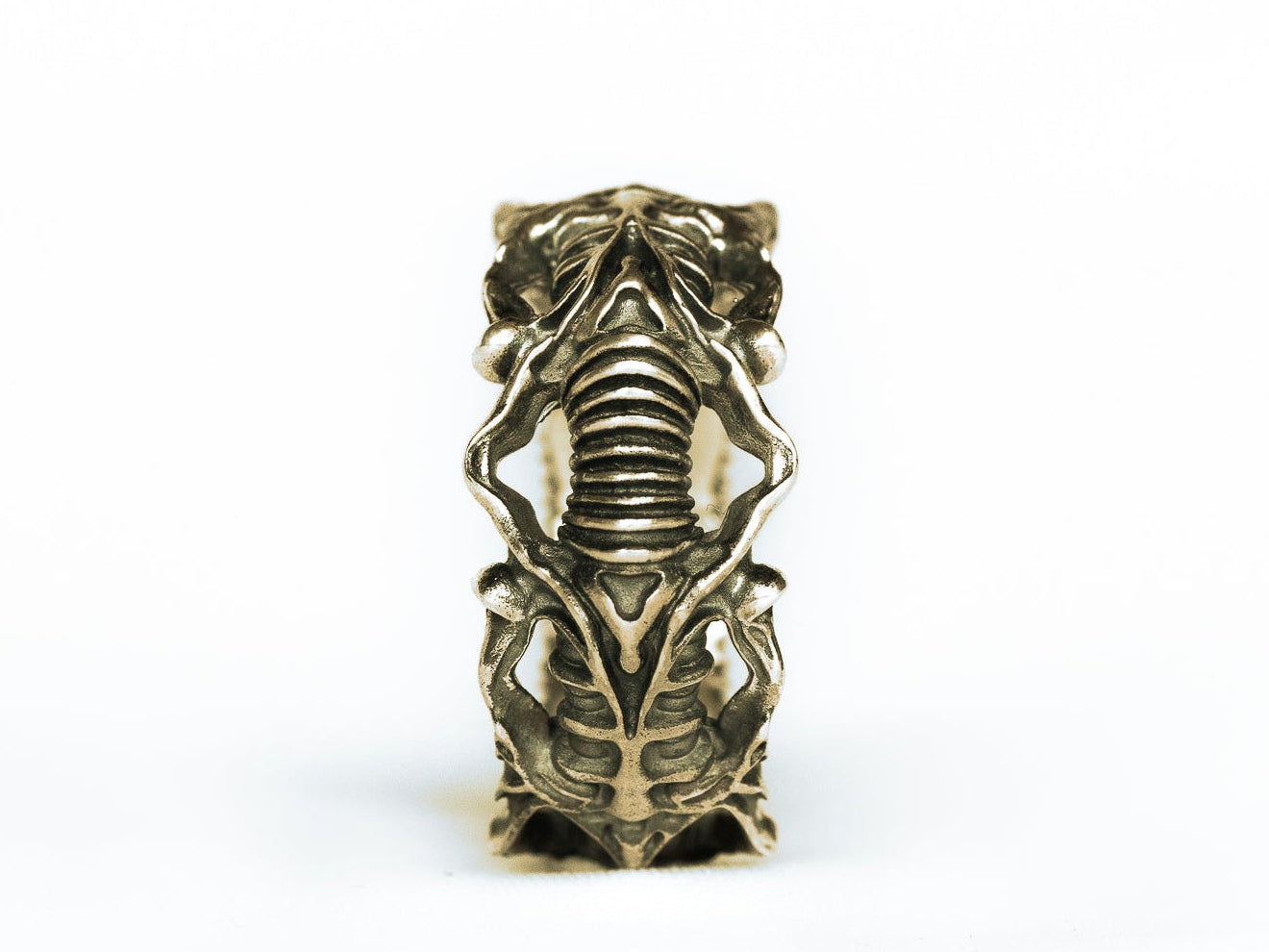 Upright BIOORGA ring with ribbed biomechanical details; digitally recoloured brass preview.